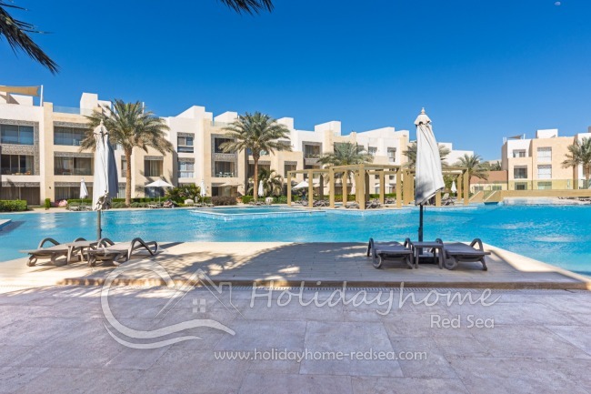 Shared pool with sunbeds and umbrellas